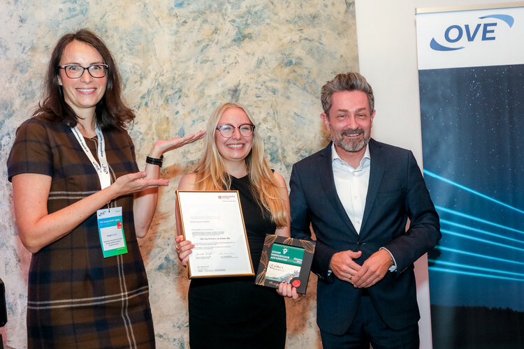 Preisträgerin flankiert von einer Dame und einem Herrn